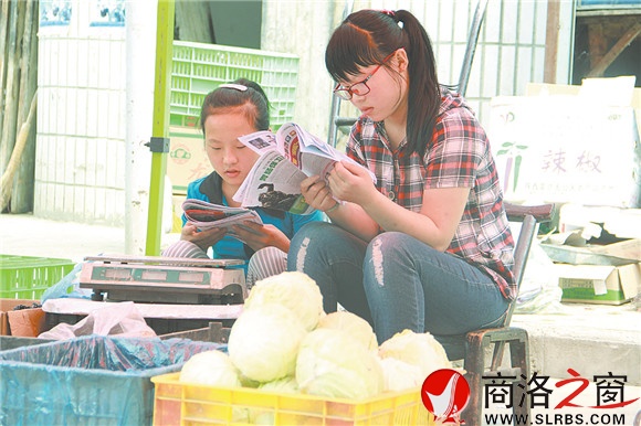 商州區(qū)楊斜鎮(zhèn)集市上，南思佳和妹妹在幫父母賣菜，閑暇之余，她們會拿起課外讀物翻一翻。在這個(gè)假期里，她們呆的最多的地方就是這個(gè)菜攤。